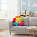 Colorful smiley face pillow on a gray sofa in a child-friendly room with books and toys.