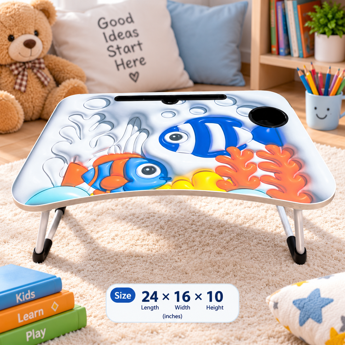 A children's lap desk with an underwater fish print, shown in a styled bedroom setting. The desk has a white base with colorful cartoon fish, coral, and bubbles, supported by silver metal legs with black feet.