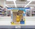 A boxed toy aircraft with a Pikachu figure inside, displayed on a store shelf with blurred toy shelves in the background.