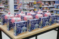 Row of TG48 Planet Bubble Machine boxes on a table with a store shelf in the background.