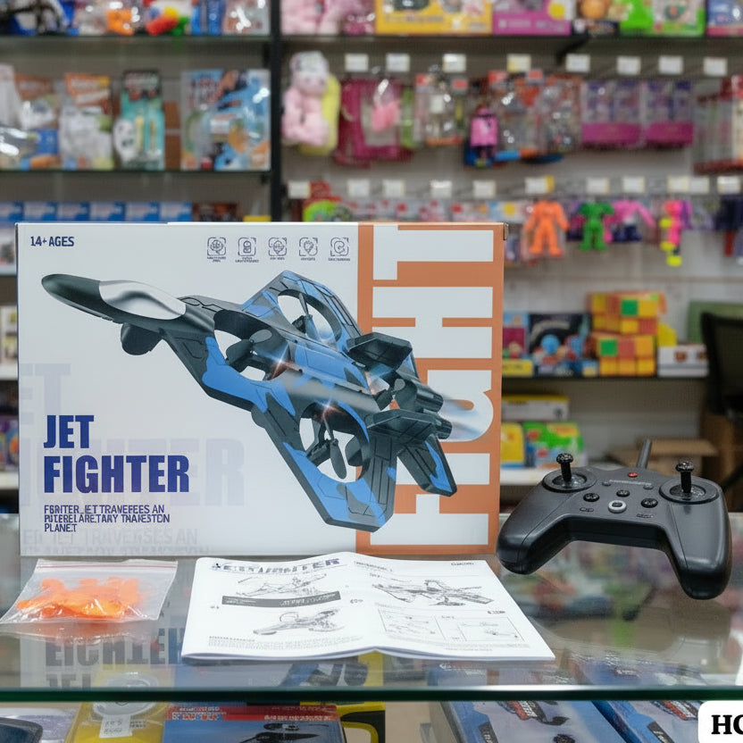 A boxed jet fighter remote control toy set displayed on a glass shelf in a toy store, with the product box, black remote controller, instruction booklet, and small orange accessory bag in front of blurred toy shelves.