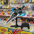 A toy replica sword with blue and black wing-like blades and a black stand, shown alongside a black remote control in a toy store setting.