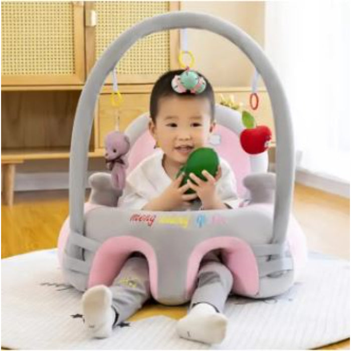 Child sitting in a baby seat with toys, indoors.