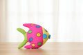 Colorful fish-shaped plush toy on a wooden surface with a light background