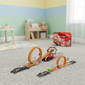 Toy construction set with tracks and vehicles on a carpeted floor in a child's room.