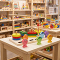 Colorful wooden educational toys on a table with shelves of more toys in the background