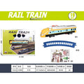 Toy train set packaging and contents on a white background with a green header reading 'RAIL TRAIN'. The set includes a yellow, blue, and white train car, a blue curved track piece, a small scenery piece, and accessories.