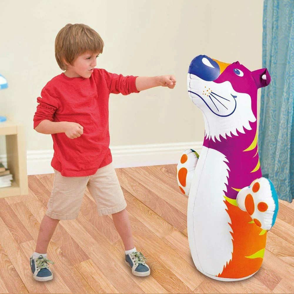 Child playing with a colorful inflatable punching bag shaped like a dog in a room.